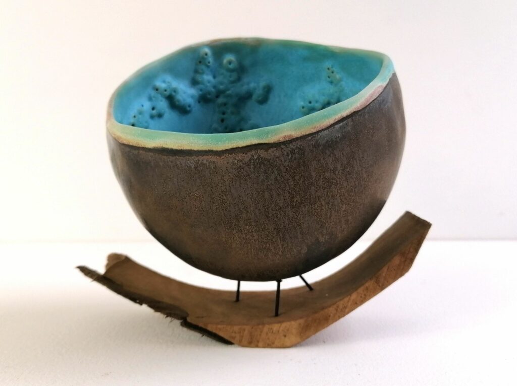 demi sphère en grès avec des émaux dorés à l'extérieur et turquoise à l'intérieur, posée sur trois clous et une écorce de bois